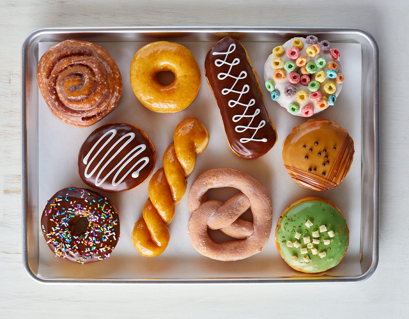 an assortment of yeast raised donuts with decorative glazes, icings and frosting