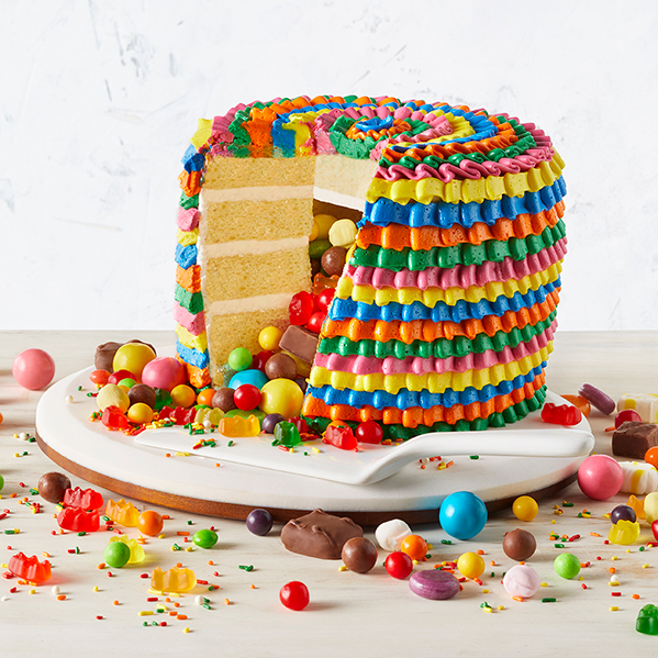 a colorfully decorated cake cut open to reveal candy inside