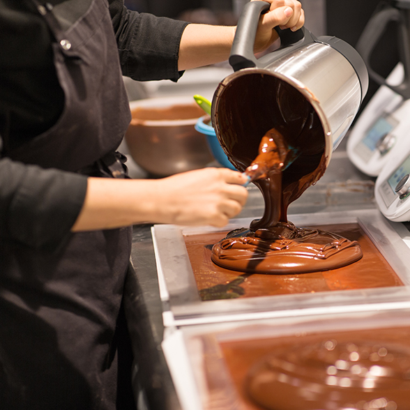 Baker pouring chocolate on to workspace