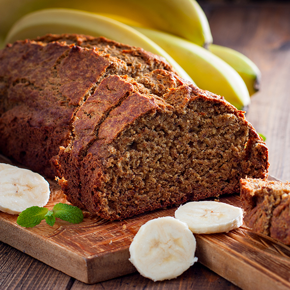 banana loaf with banana garnish on a wooden cutting board