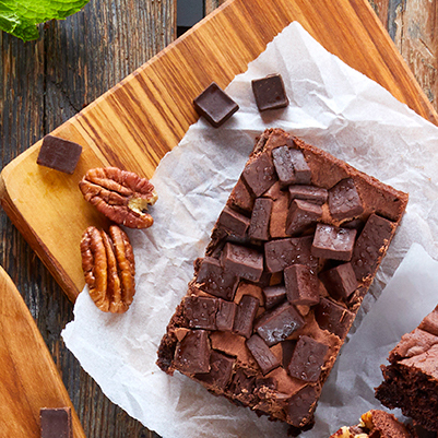 Brownie with large chocolate chunks and walnuts on parchment paper