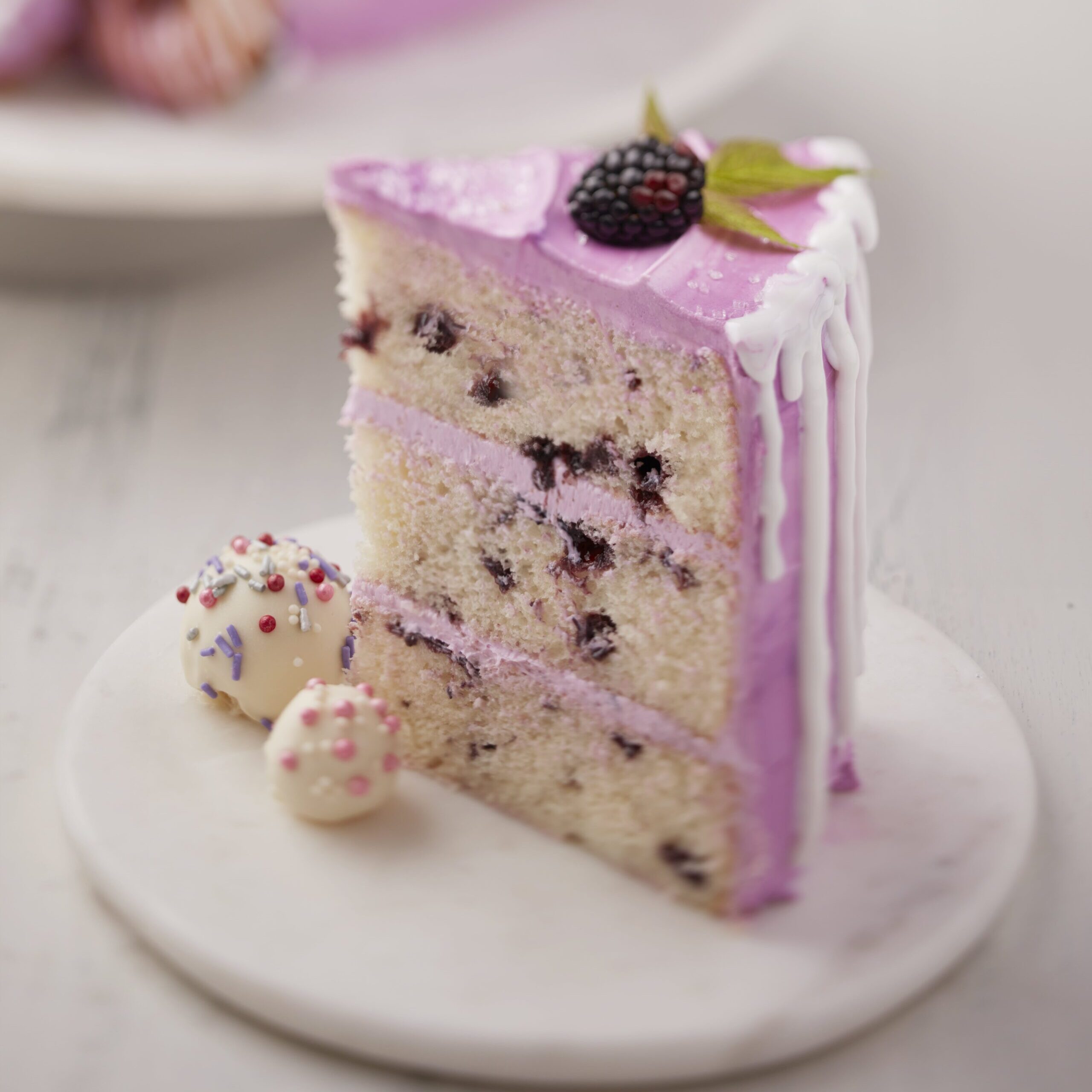 a slice of cake with blackberry frosting and decorations on a white plate