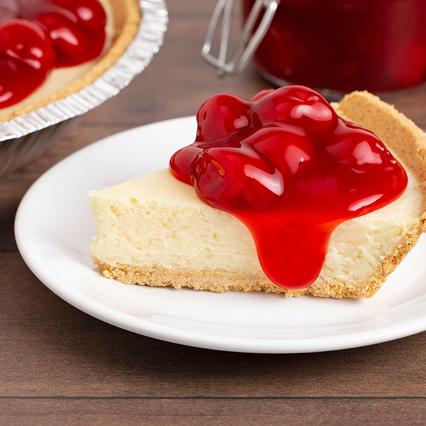 cheesecake topped with cherries on a white plate