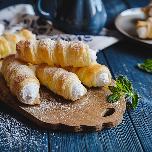 cream horns stacked on top of a wood board