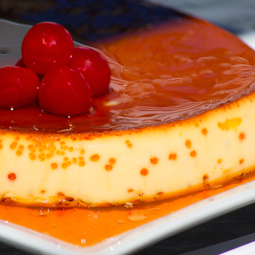 Flan on a white plate topped with cherries