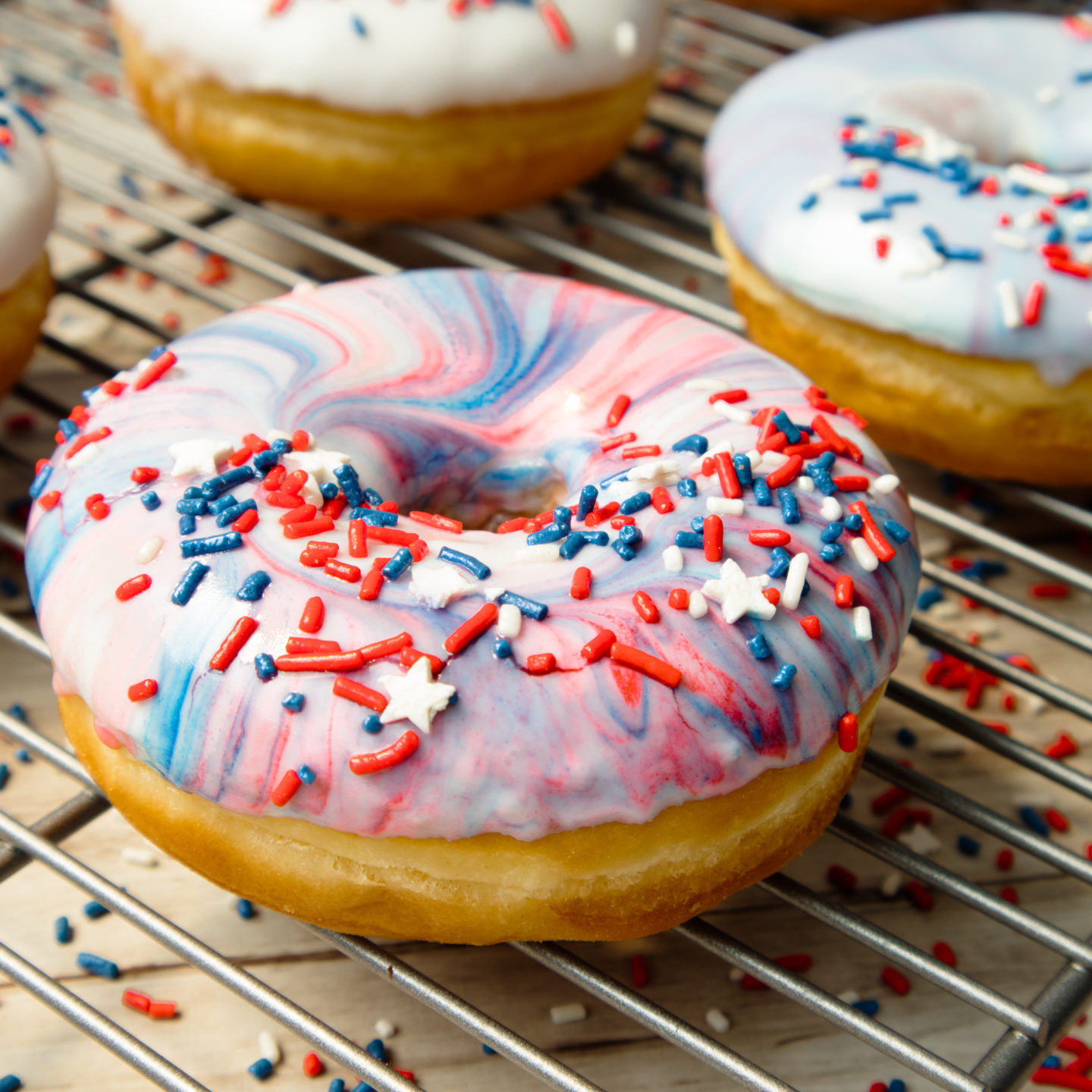 Donuts on a wire rack with red, white and blue glaze and sprinkles