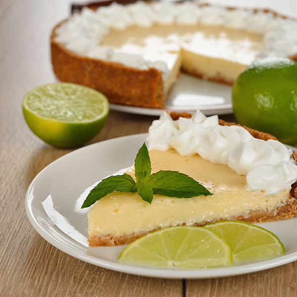 Slice of keylime pie with lime and mint garnish