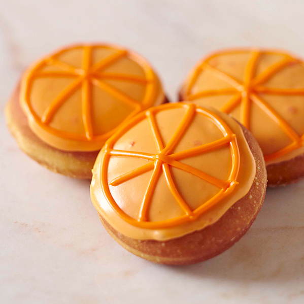 Three orange donuts with orange frosting