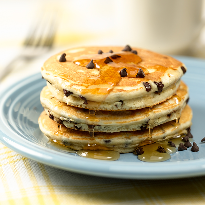 a stack of pancakes with chocolate chips and maple syrup on a blue plate