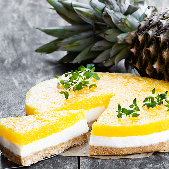 pineapple cheese cake with a slice being removed with a pineapple in the background