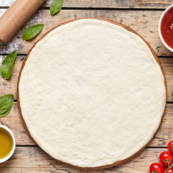 Overhead shot of uncooked pizza dough on a wood surface