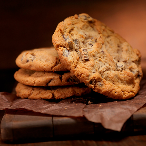 a stack of chocolate chip cookies on brown parchmen tpaper