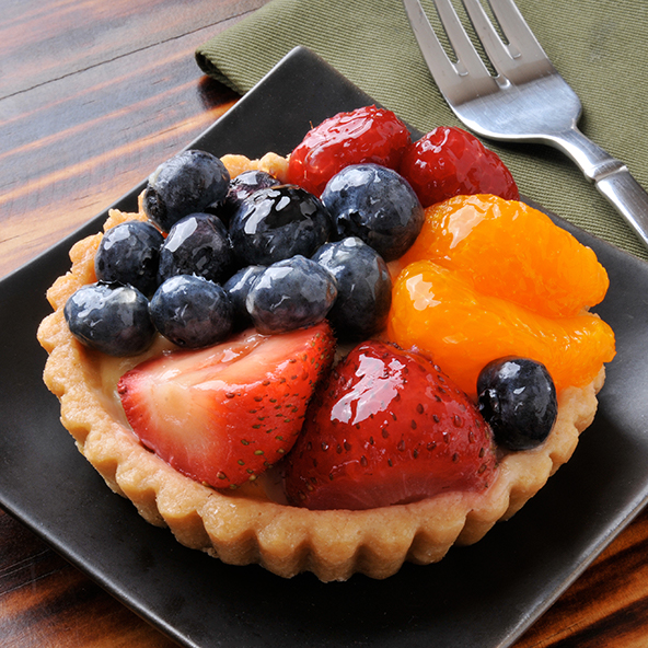 A fruit tart with glaze on a black plate