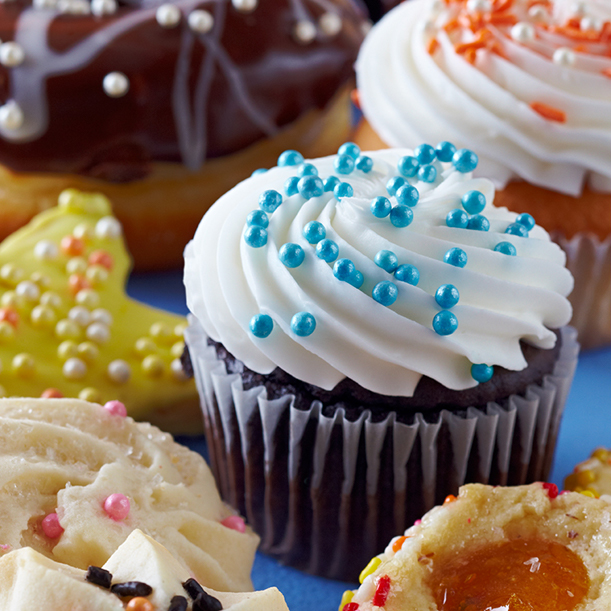 an assortment of cupcakes and cookies topped with frosting and pearls