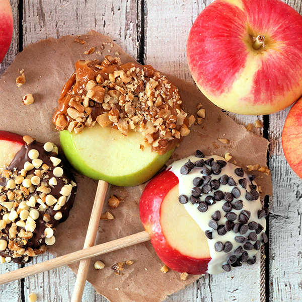 A variety of dipped apples on skewers wit frosting, caramel, nuts and chocolate chips