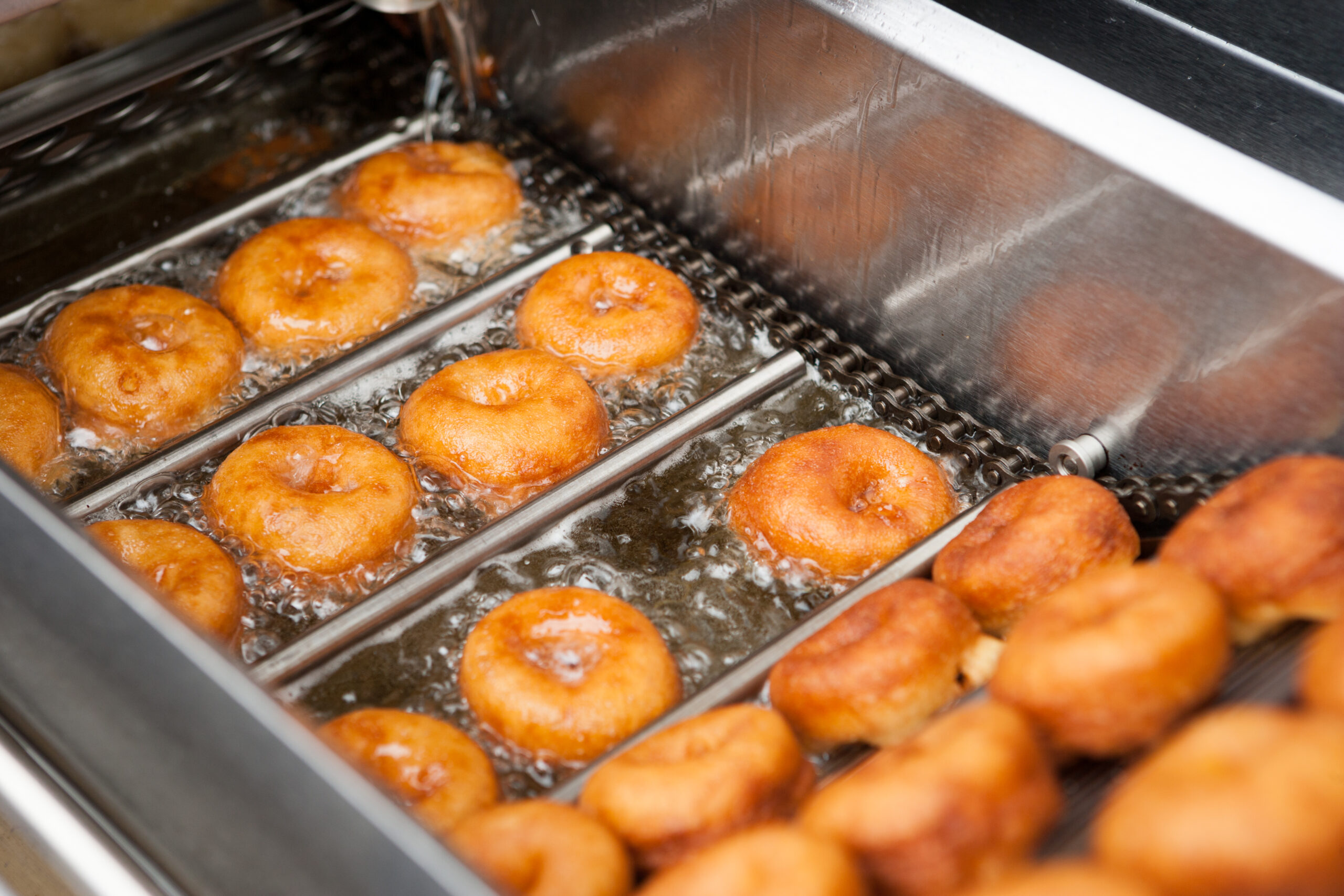 Donuts being fried in large frier