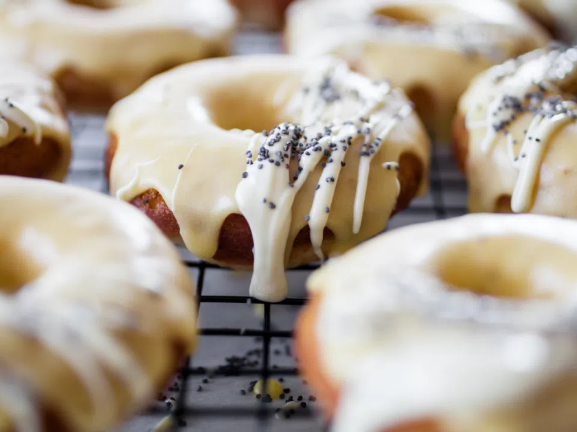 Donuts drizzled with frosting on a cooling rack